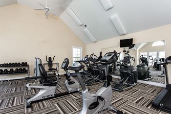 A gym with various cardio machines and dumbbells